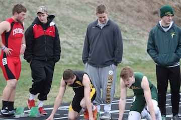 READY, SET, GO- Junior Dillon Sonntag gets set in the blocks before his 100m dash while Senior Dawson Walter holds his blocks. While Sonntag has been to State the last two years, this is Walters first year doing track. 