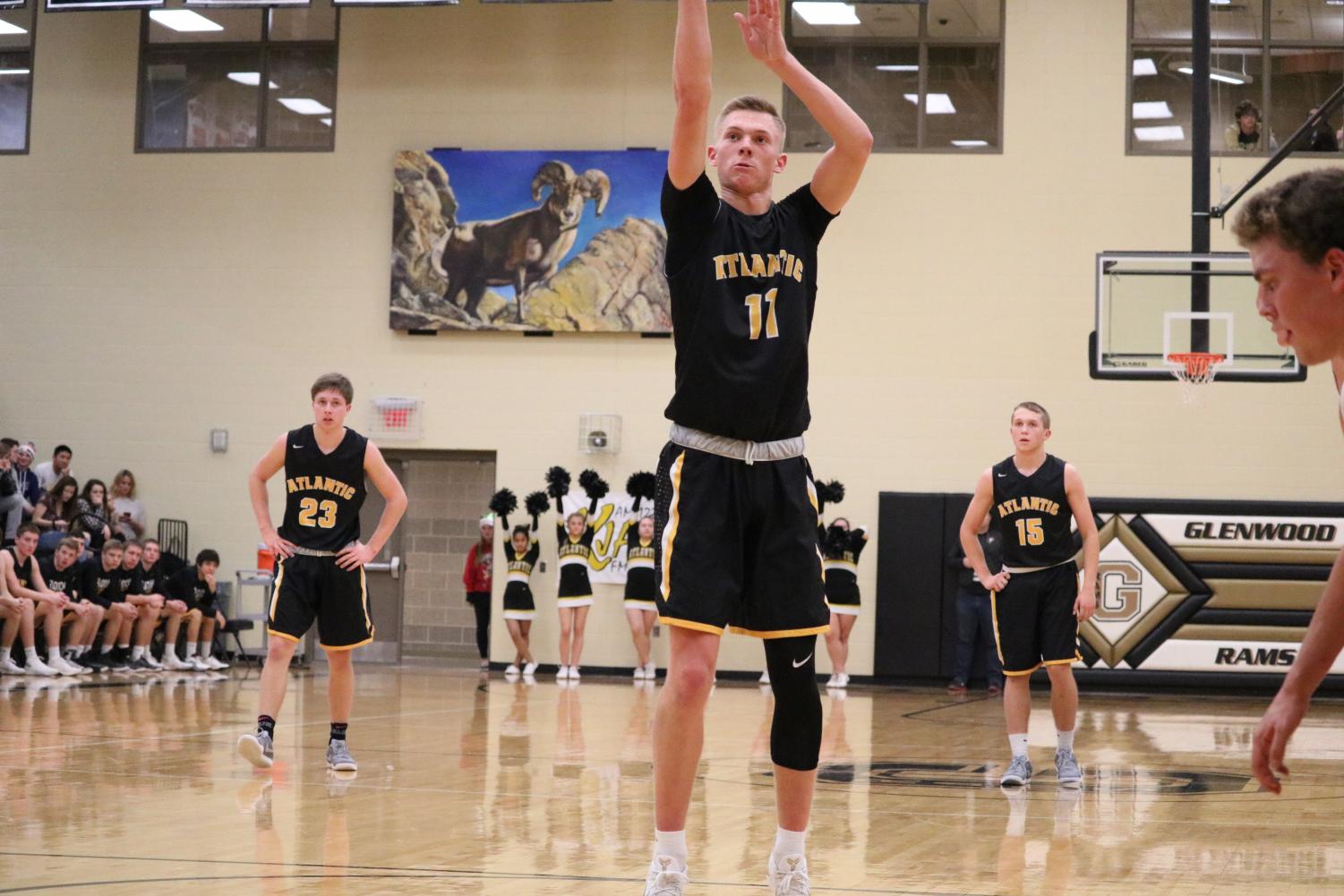 Senior Austin Alexander shoots a free throw while Senior Jaxson Eden and Sophomore Tyler Moen look on. The Trojans lost to the Rams in their first meeting 64-31.