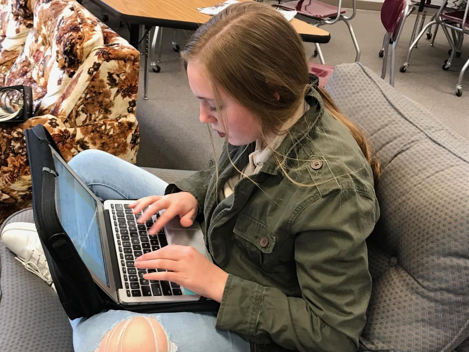WORKING HARD - Alyssa Brockob writes on her laptop during free time in class. Students who submitted work to Hot Dish used pieces made in and out of school.