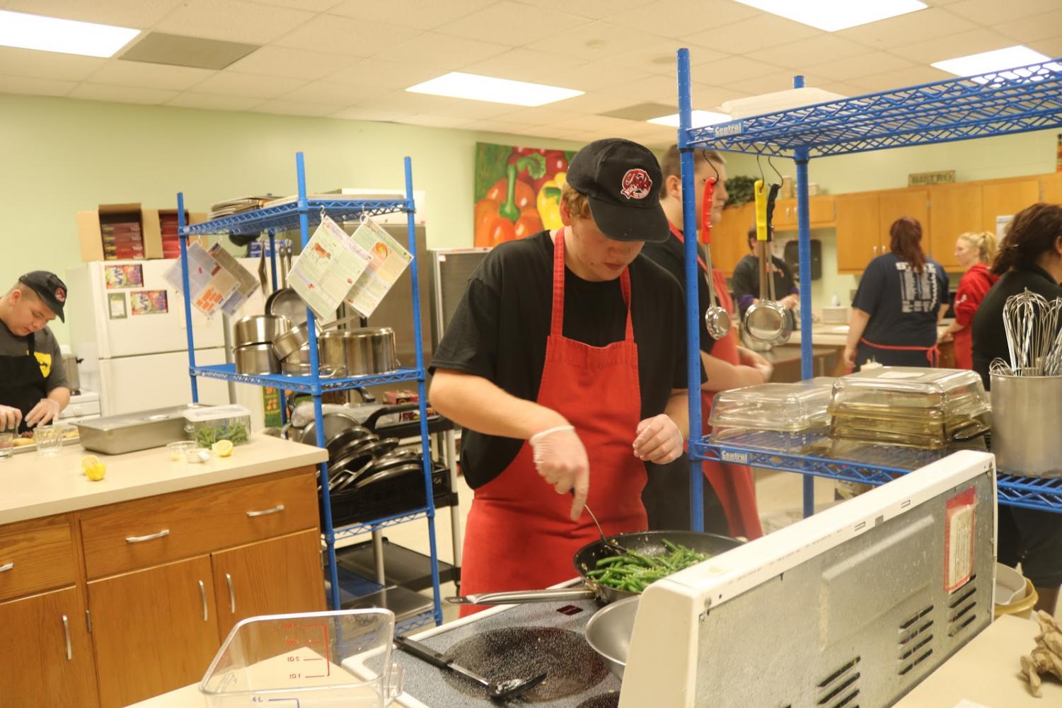 CRUNCH TIME - Junior Christian Clausen tends to vegetables that are part of the recipe for Trojan Diner. The Diner is held a total 8 times throughout the school year. Students in Foods 2 pick, plan and prepare the first four meals, while students in International Cuisine are in charge of the final four.
