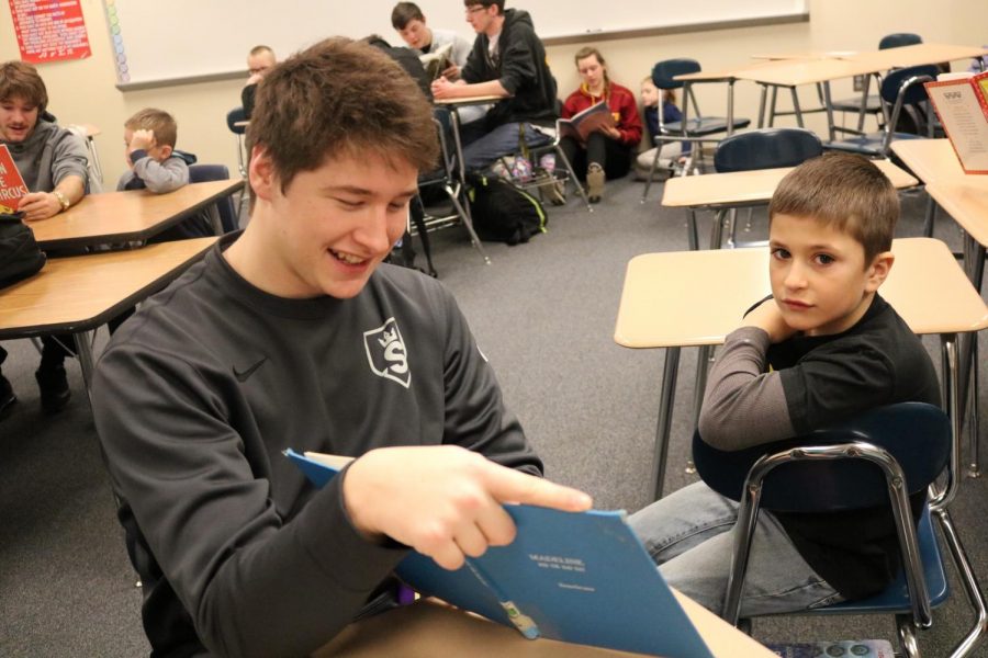 Junior Korben Petersen smiles while reading to Washington student.