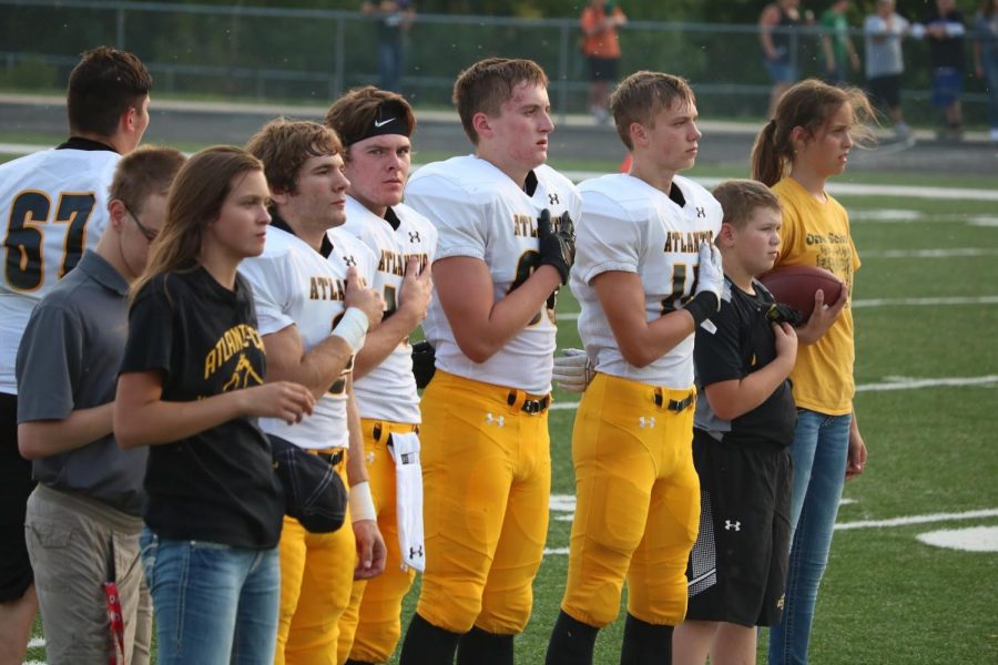 Senior players stand with their hands over their hearts as the National Anthem plays before the game against Saydel.