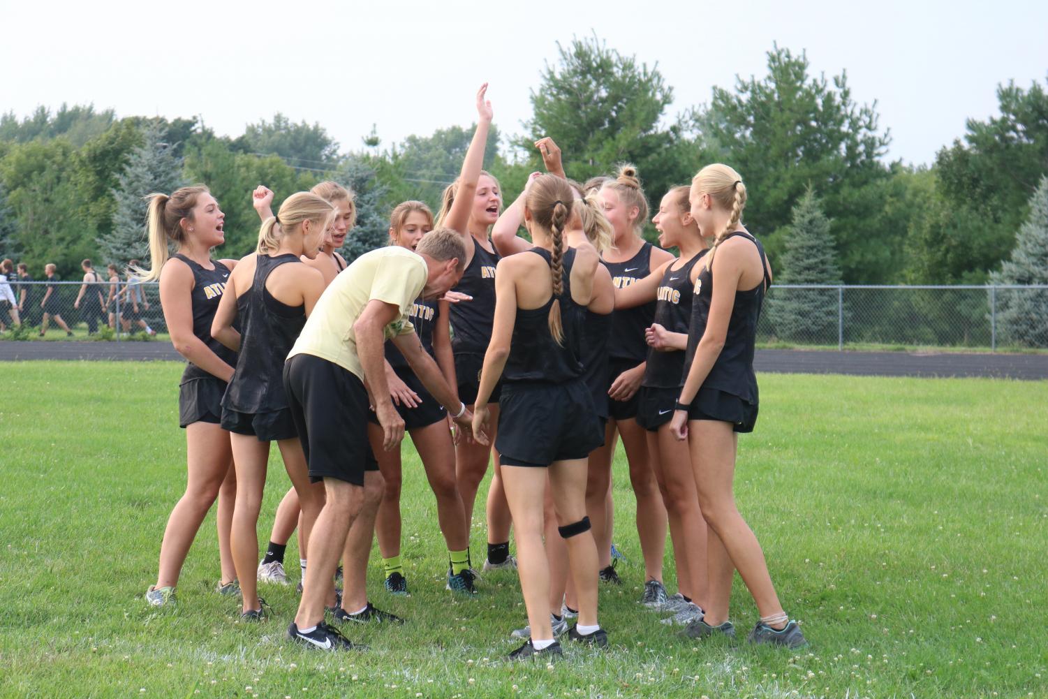 HANDS IN-- Members of the girls cross country team break down with assistant coach Brad Rasmussen before running the time trial course.