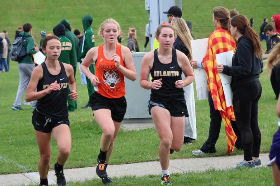 TEAMWORK - freshman Addie DeArment and junior Katie Saluk pass a competitor at the home meet. The girls team placed fourth in a field of 20.