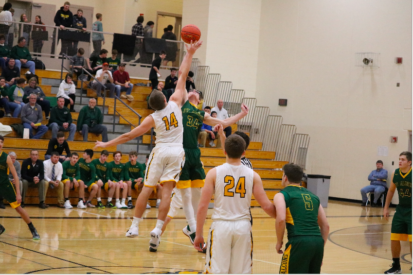 JUMPMAN - Junior Tyler Moen leaps to grab the ball at the beginning of the game. Moen has been an asset the basketball team for three years. 