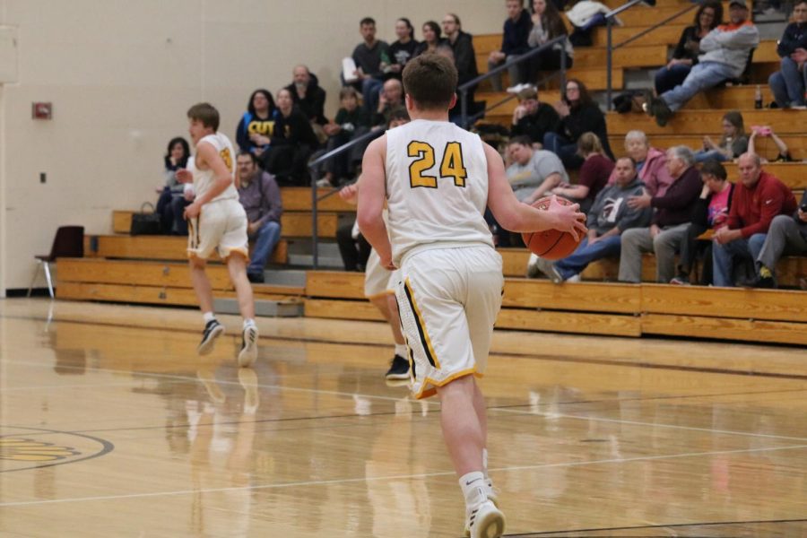 Senior Logan Reilly dribbles the ball up the floor in the Trojan gym. Currently, he leads his team in rebounds with 130.