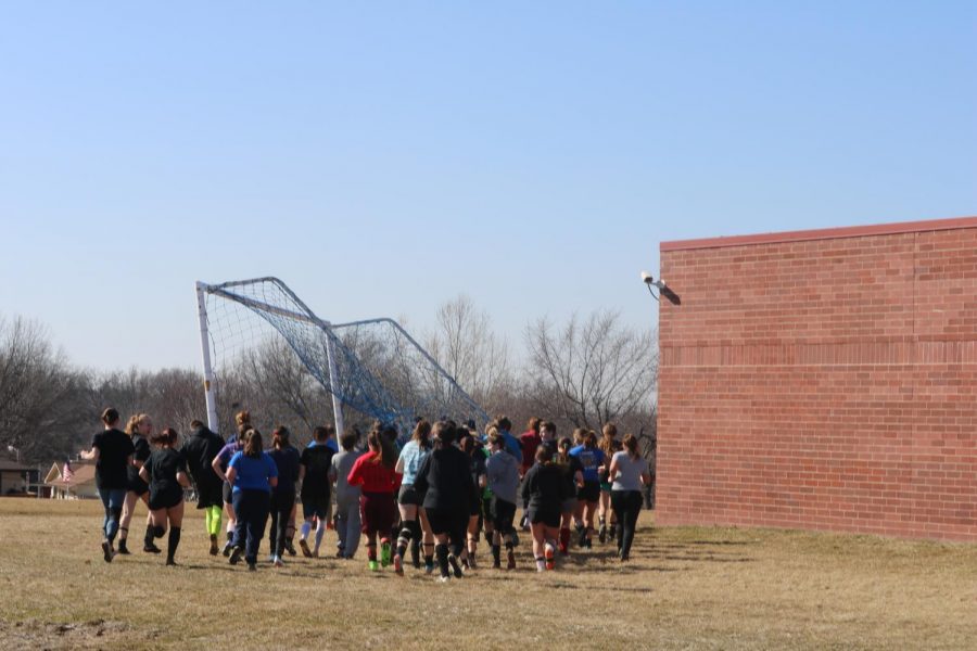 SOCCER KNOWS NO GENDER -- The boys' and girls' teams work together to bring a net from the game field to the practice field.