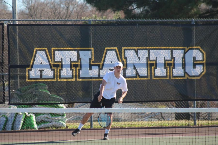 Junior Nile Petersen swings through his serve at the Washington tennis courts. Petersen is undefeated at the #1 spot. 