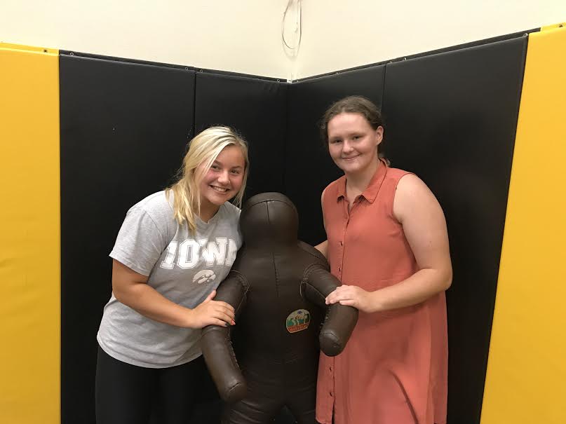Sophomores Kenzie Hoffman and Lexie Trotter pose in the wrestling room. Both girls are committing to wrestle this season.