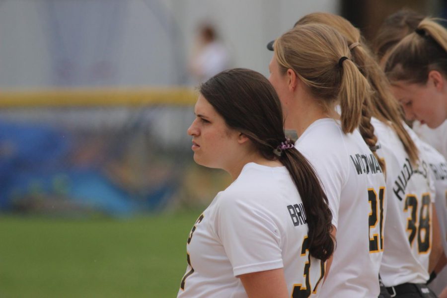 The softball girls watch the opposition during warmups. 