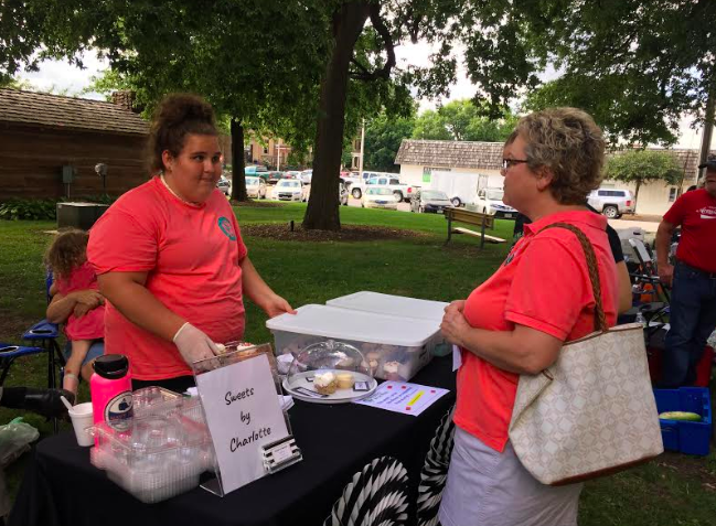Charlotte Saluk assists a customer at Produce in the Park last summer. Saluk would sell her goods, as well as answer questions on her business and recipes.