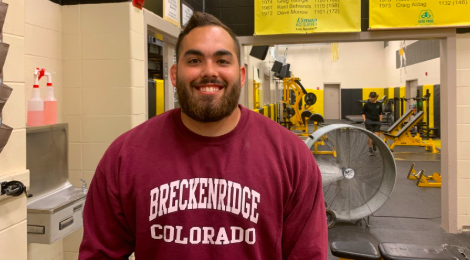 Connor Larson stands in the weights room. Besides coaching weights and wrestling, Larson also teaches PE.