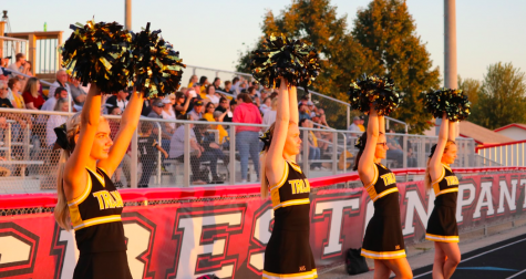 The cheerleaders stand ready at a football game this season. Behind the scenes, the squad makes snacks and posters.