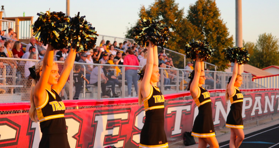 The cheerleaders stand ready at a football game this season. Behind the scenes, the squad makes snacks and posters.