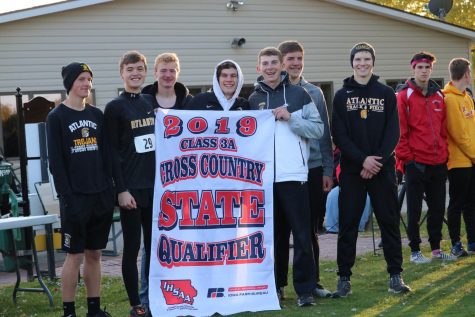The boys cross country team hoists their state-qualifying banner up. This is the second year in a row the boys team has made an appearance at state.