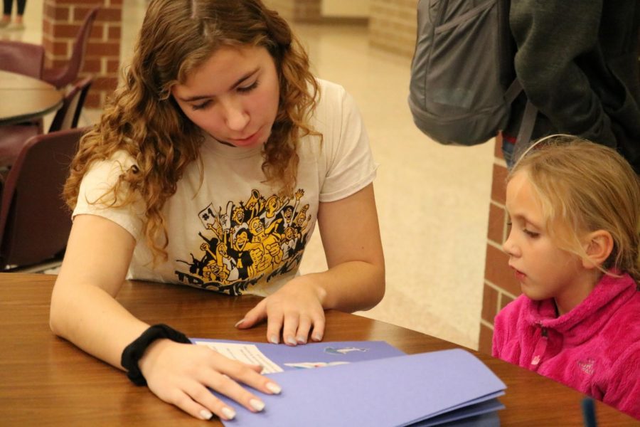 Junior Hannah Carlson reads her creation to her first-grade reading buddy. 