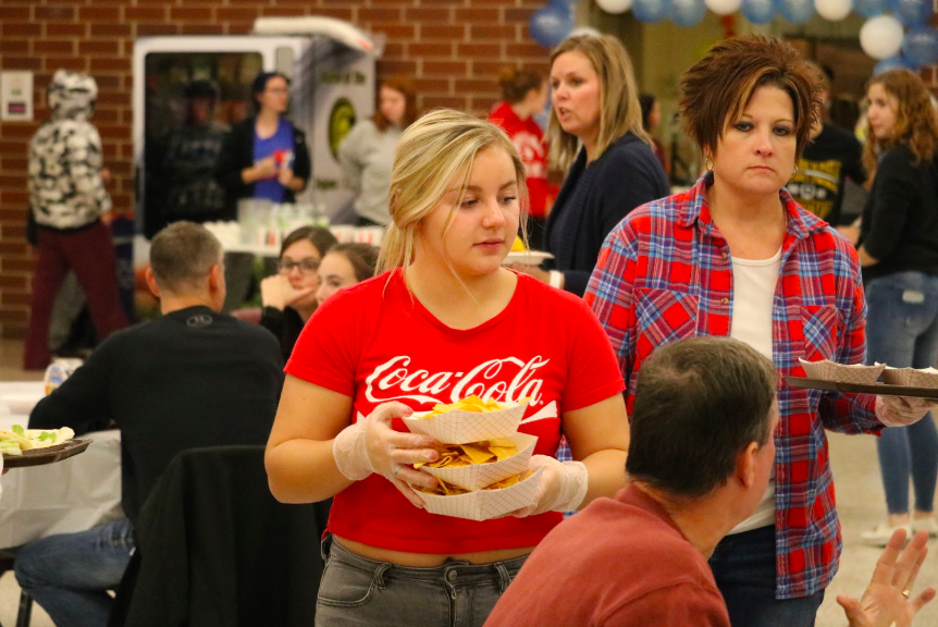 Sophomore Kenzie Hoffman serves plates of chips at the Taco Night fundraiser. All students who participated took tickets, made food, or served those attending.