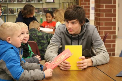 Junior Garrett Reynolds shares his children's book with two first graders. Reynolds is involved in a variety of sports.