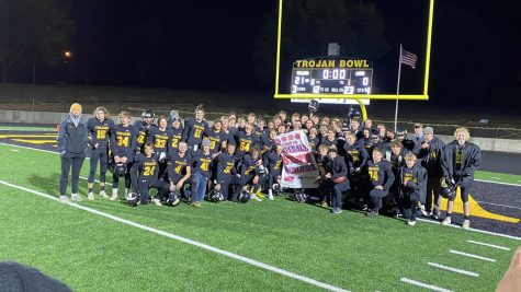 The football team poses for a picture with their state-qualifying banner. This is the first time in 18 years the Trojans qualified for state.