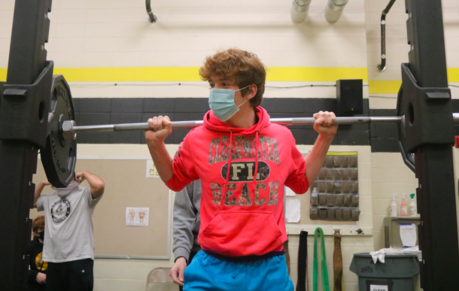 MASK UP - Isaac Henson wears his mask to stay safe during the pandemic. He chose to back squat part of the class. After lifting, students clean down all of the used equipment. 