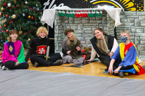 Sophomores Kylie Pulido, Cater Pellett, Reece DeArment, Charolette Saluk, and Micaiah Anderson sit around a fake fireplace while a Christmas tree twinkles in the background.  Pulido and Anderson played Jesters for the Madrigal.