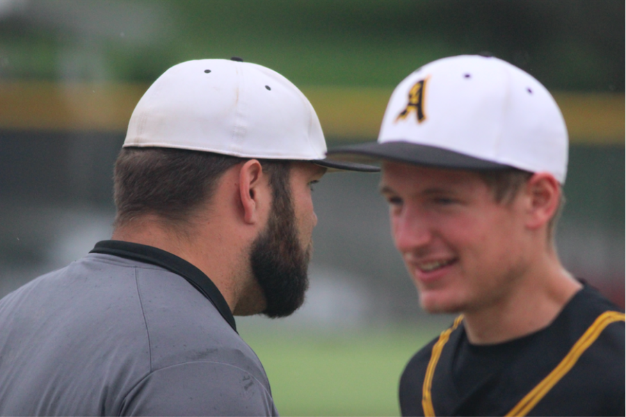 Baseball coach Joe Brummer speaks with graduate Nathan Behrends at a baseball game. 