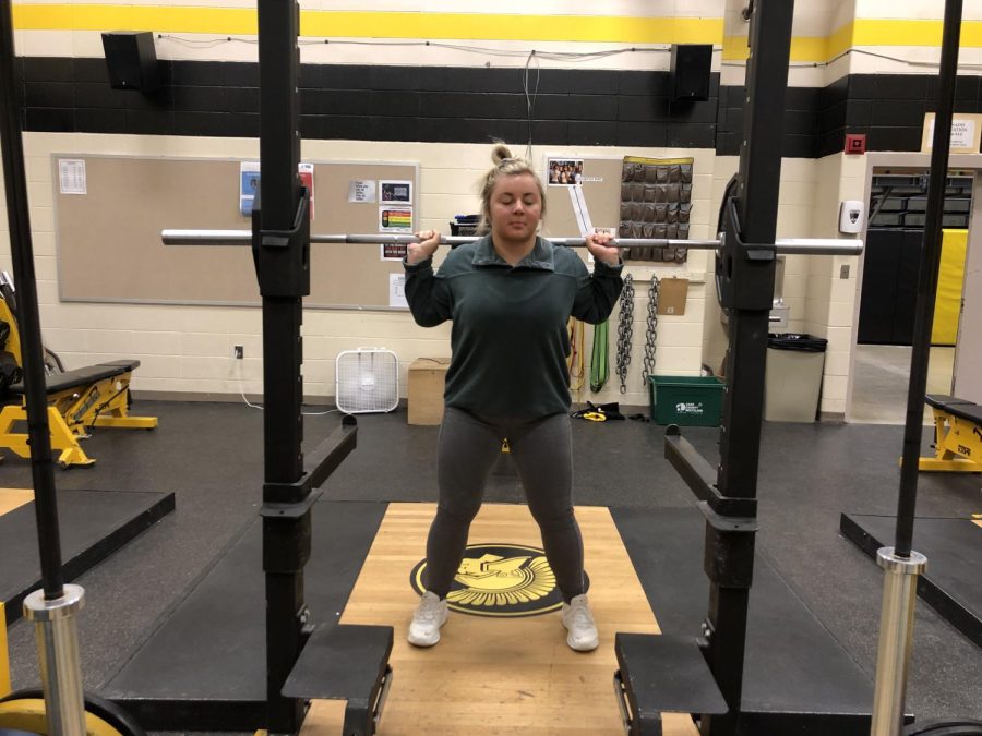 Senior Kenzie Hoffman warms up with squats in the AHS weight room. Hoffman started lifting at 13 years of age. Her max squat is 245.  