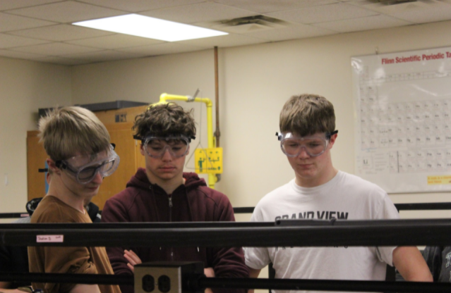 Juniors Jadyn Cox, Cole Park, and Brenden Casey watch as their pennies change. The students placed a layer of zinc on a copper penny and heated it up. This allowed the materials in the coin to mix. 
