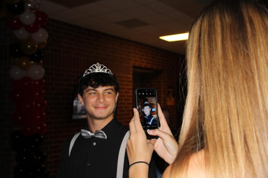 PASS IT ON -- Senior Rio Johnson photographs freshman Keelin Rasmussen wearing her homecoming queen tiara. Throughout the night, Johnson took dozens of pictures of different students wearing the crown for a TikTok she made.