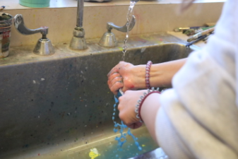 Freshman Cali Thompson washes her hands after doing a project with her friend. Art can bring many people together.