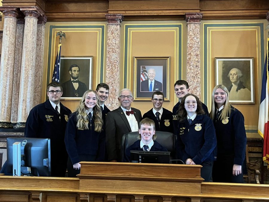 FFA members in the House of Representatives. From left to right: DJ Shepperd, Claire Pellett, Daniel Fruend, Representative Tom Moore, Colton Rudy, Jackson McLaren, Charli Goff, Callee Pellett. Seated: Dylan Comes.