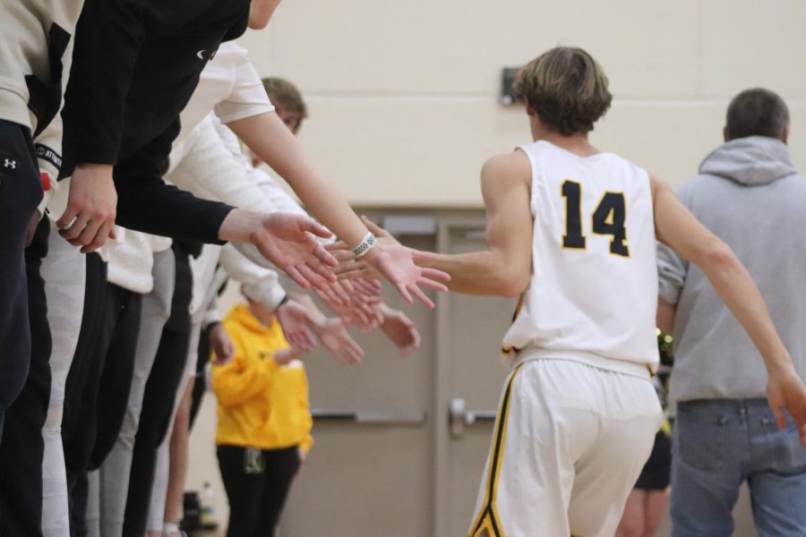 Colton+Rasmussen+high-fives+fans+at+a+basketball+game.+Parents+and+students+alike+cheer+on+athletes+from+the+stands.