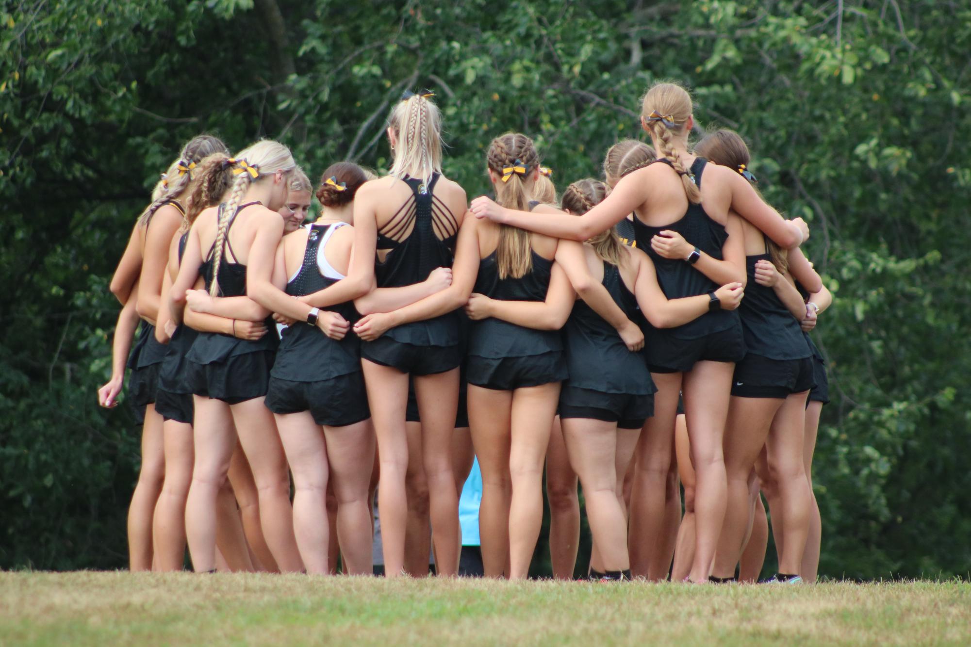 RACE READY - The girls cross country team huddles around each other before the start of the race. There were record numbers of girls out for the team this year.