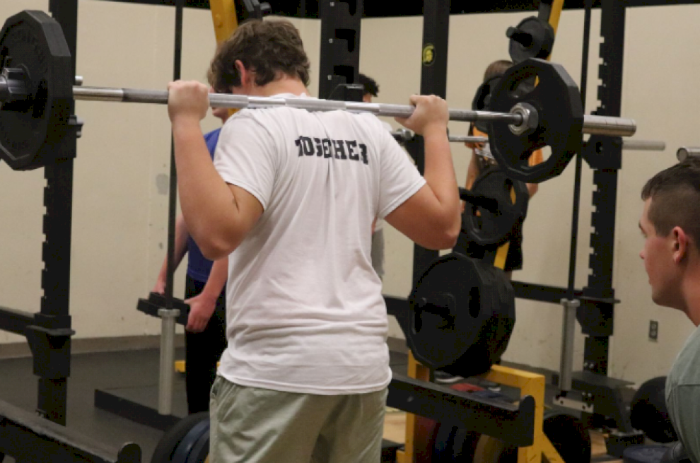 GETTING WARM - Sophomore Matt Pollock warms up with 25lb plates on each side. Later, he hit a new max of 325lbs. Weights teacher Matt Best stressed the importance of a proper warm-up.