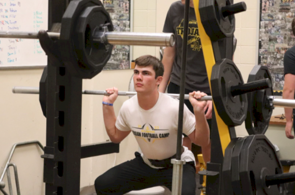EYES UP- Freshman Jake Wailes focuses on a spot on the wall while he squats to help him lift the weight. Wailes put on the lifting belt to help support his back. He did this before his lift as he works towards getting a new PR.