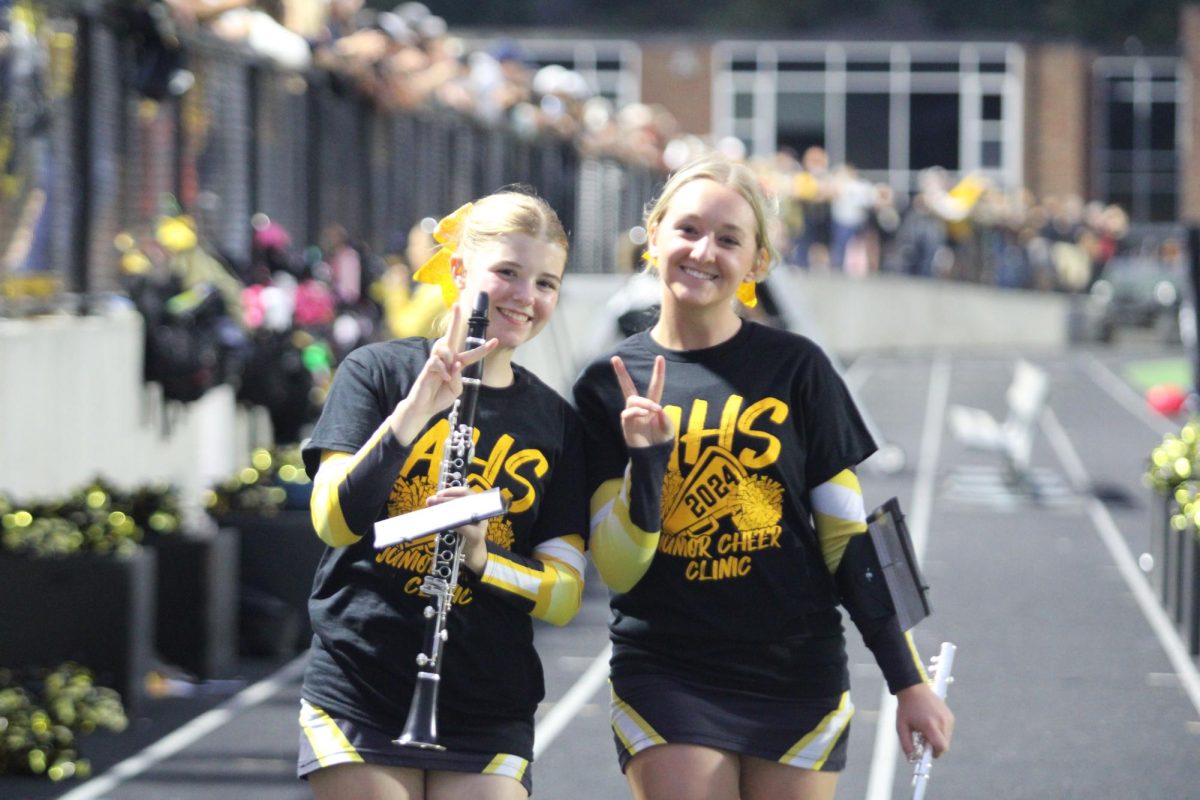 Cheerleaders Jayna McEntaffer and MaKenna Shroeder grab their instruments and prepare to enter the field to perform at halftime.