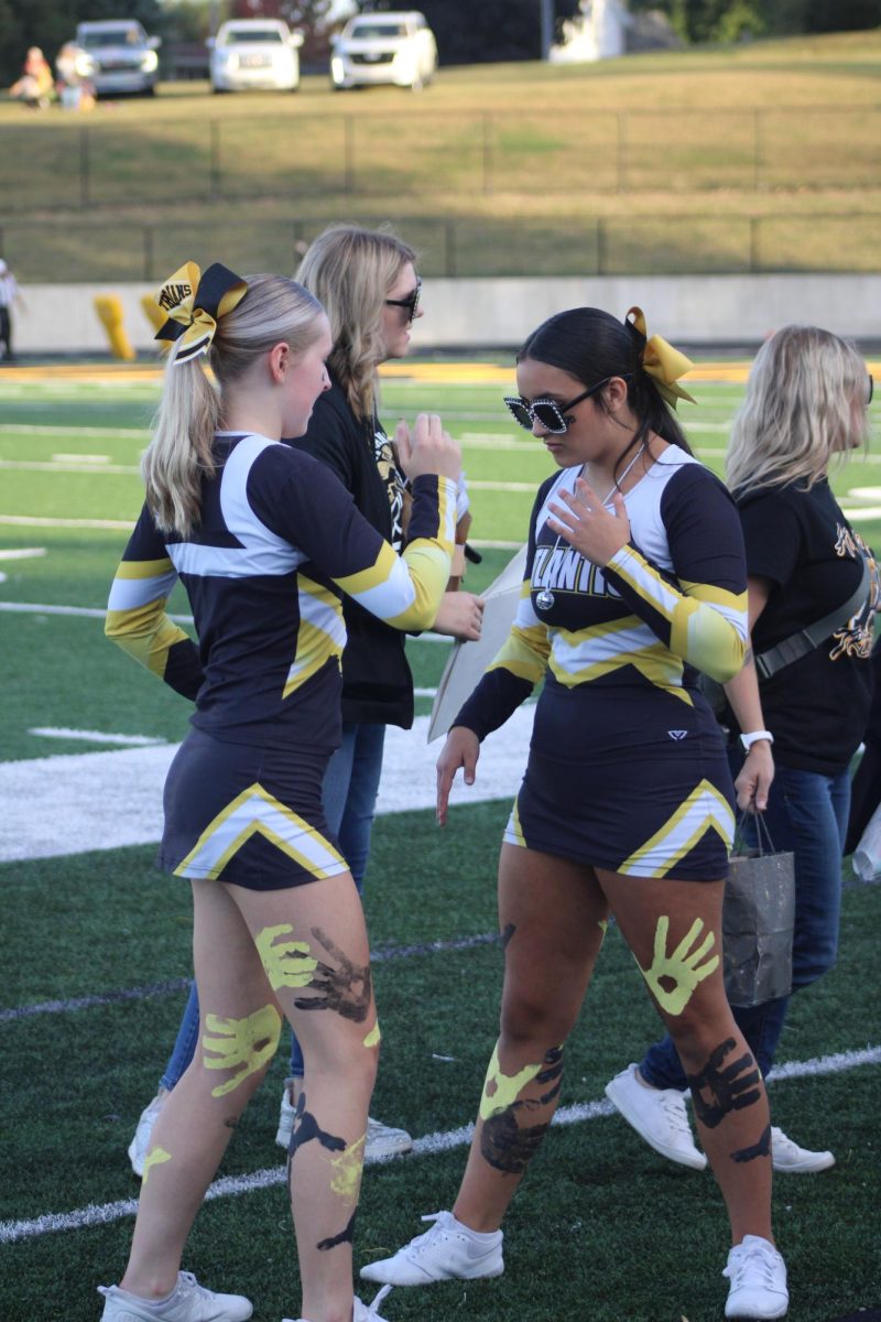 AHS varsity cheerleaders Payton Burg and Gabriella Mendez get ready to perform during the homecoming football game.