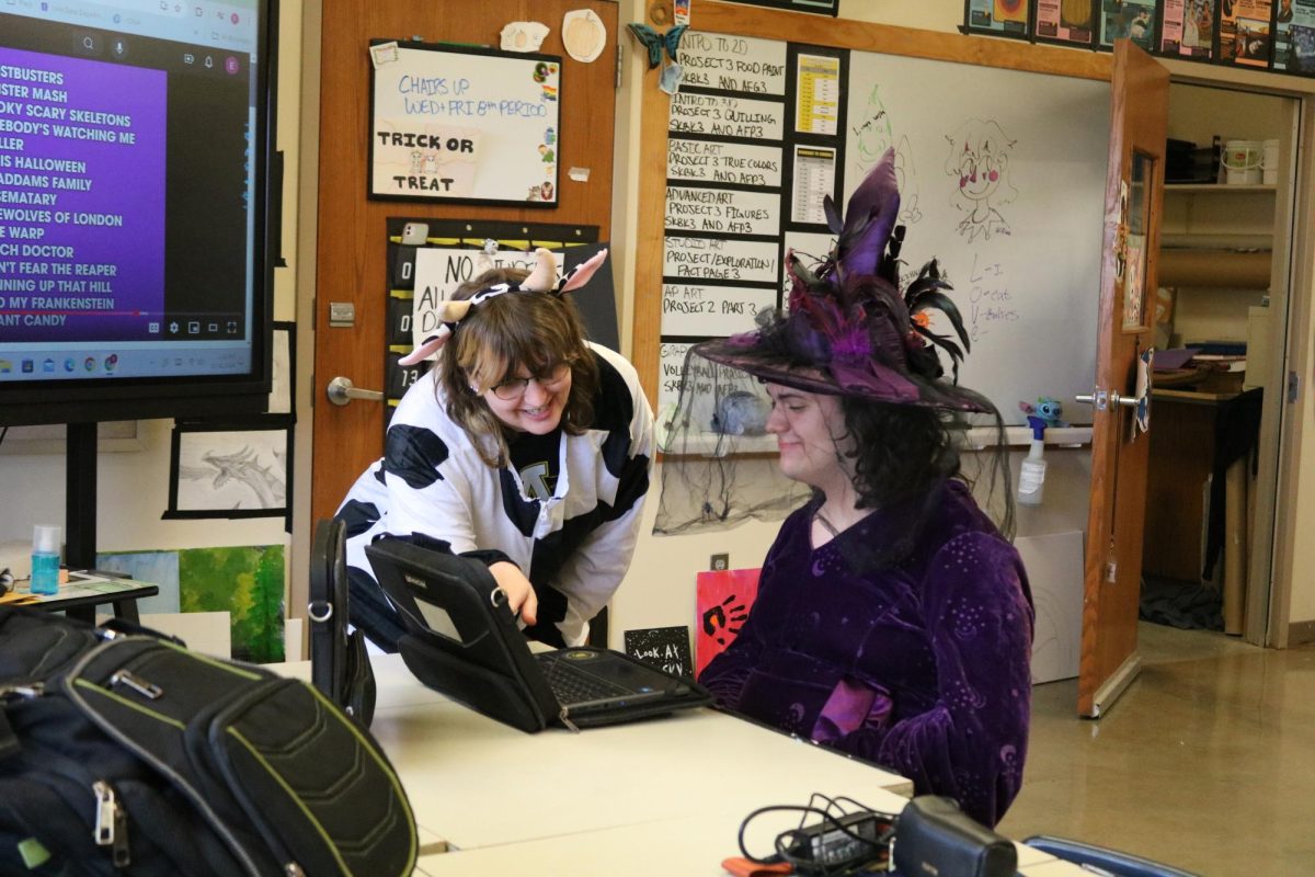 Sophomore Jordan McCool gets help from Mrs. Herrick- Williams. They are dressed up as a cow and witch for Halloween!