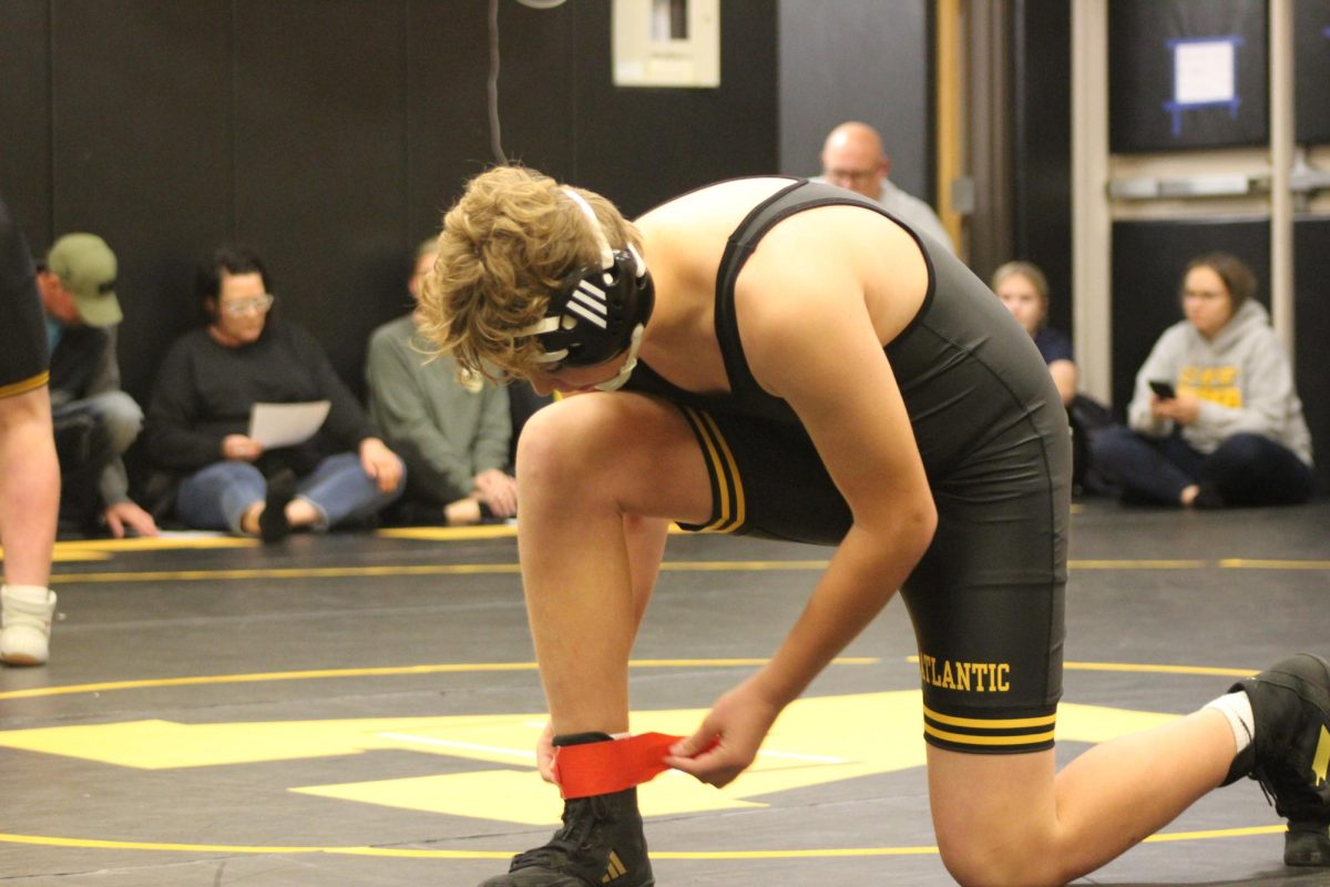 Freshman Callan Kluever puts on a leg band. Wrestlers wear the leg band so the referees know who to give the earned point to. Kluever then went to the line that matched the band. 