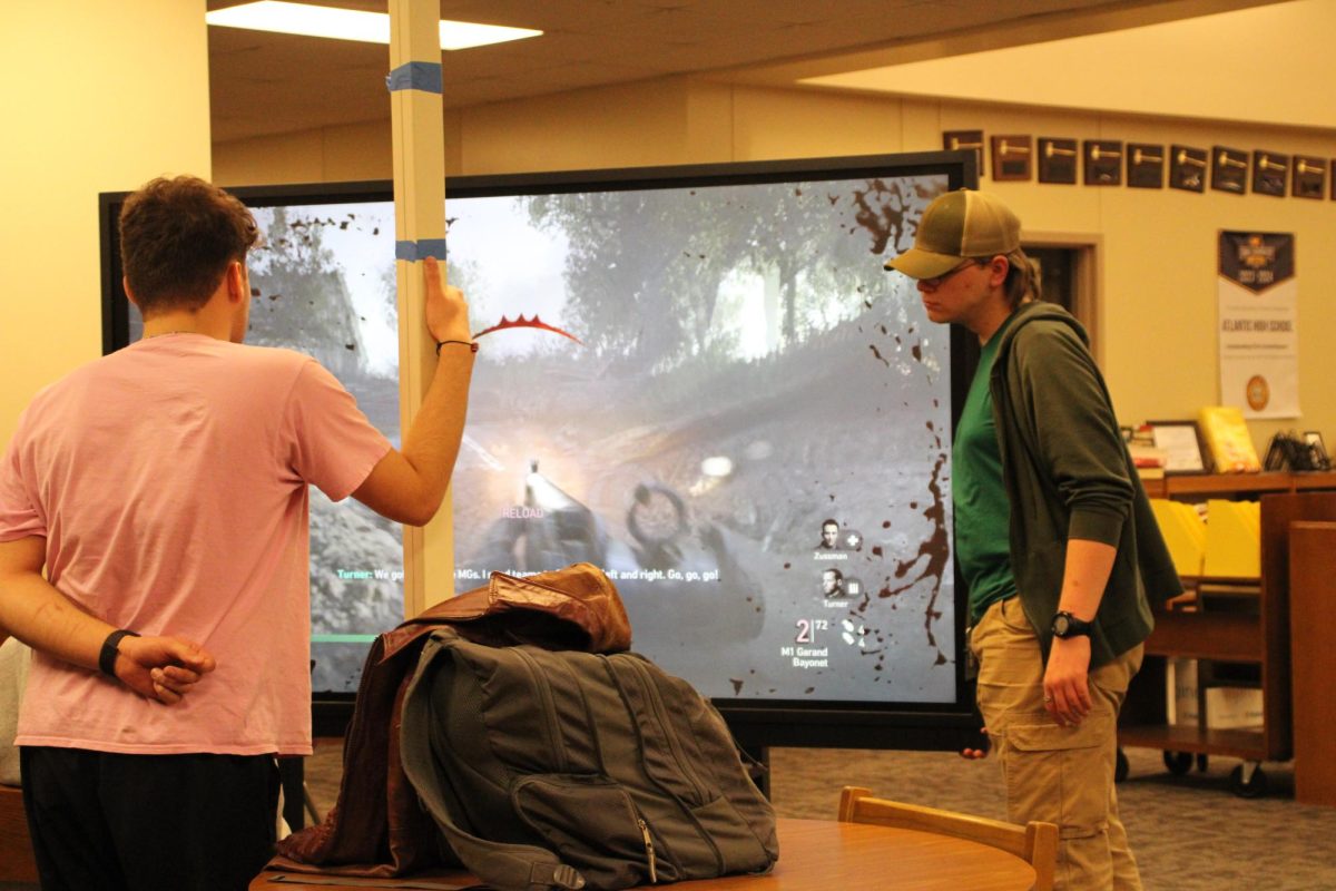 GATHER 'ROUND - Noah Huddleson watches the game while Alex Hayward approaches to survey the scene. The session caught his eye, and he couldn't help but sneak a peak before heading off again. Game Club takes place every Tuesday and Thursday from 3:13 p.m. to 5:30 p.m.