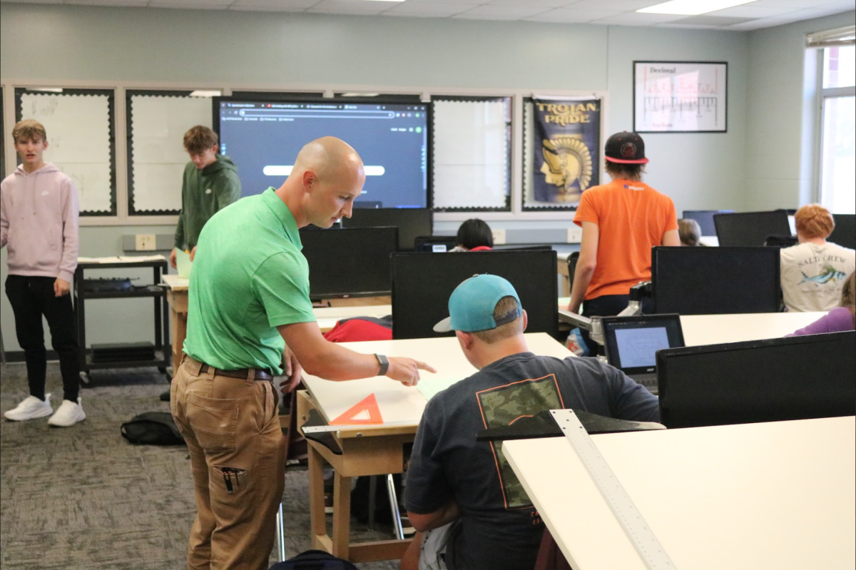 Mr. Dodson helps a student with his work. Dodson explained to him what he wanted on the paper. The student completed the assignment with no trouble.