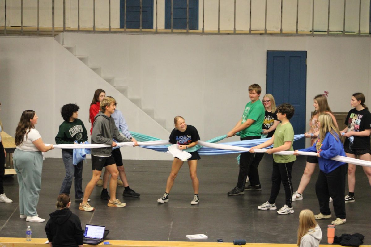 The Mamma Mia musical cast practices their group choreography. In the center, Megan Birge smiled while she was pulled in either direction by ribbons.