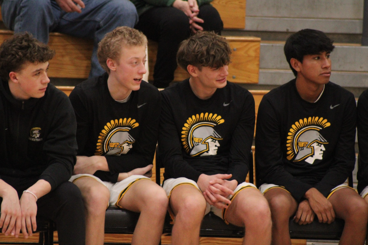 Players Kale Jensen, Vincent Meisinger, Corbin Ritter, and Devon Fields cheer on their team while watching from the bench. 