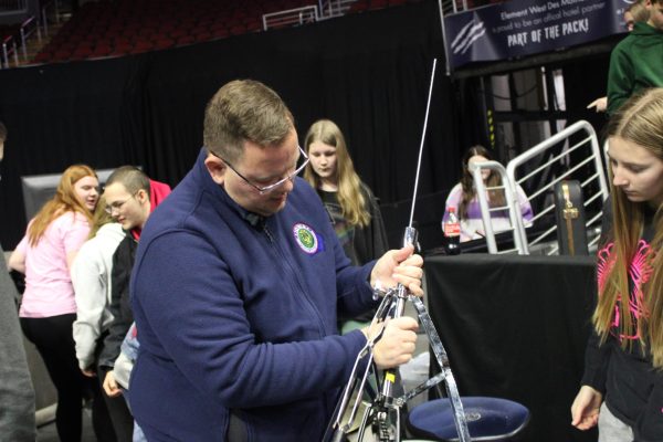 Band director Mr. O'Donnell helps percussion students set up their instruments at the Wells Fargo arena for their pep band performing.