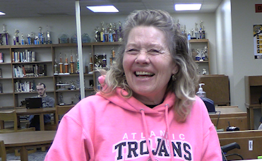 AHS Custodian Tracy Jacob smiles with students in the library.