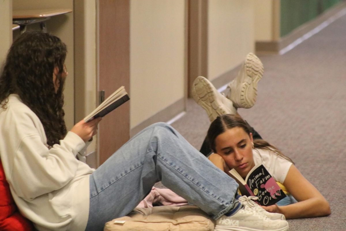 Claire Comes and Saige Coffman enjoy reading their books in the hallway. 