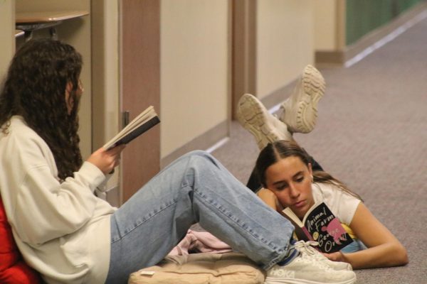 Claire Comes and Saige Coffman enjoy reading their books in the hallway. 