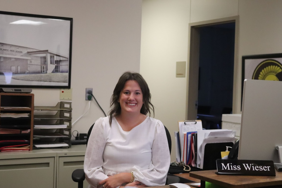 Anna Wieser smiles for a picture while sitting at her desk in the front office. 