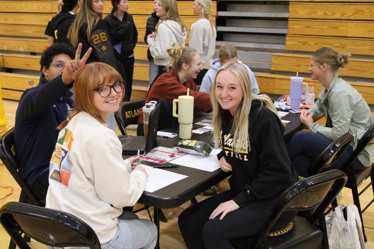 Margaret McCurdy and Makenna Schroeder enjoy the comrodorie  of working on the blood drive. Donovan Hedrington photo-bombed his fellow NHS members by popping out bunny ears.