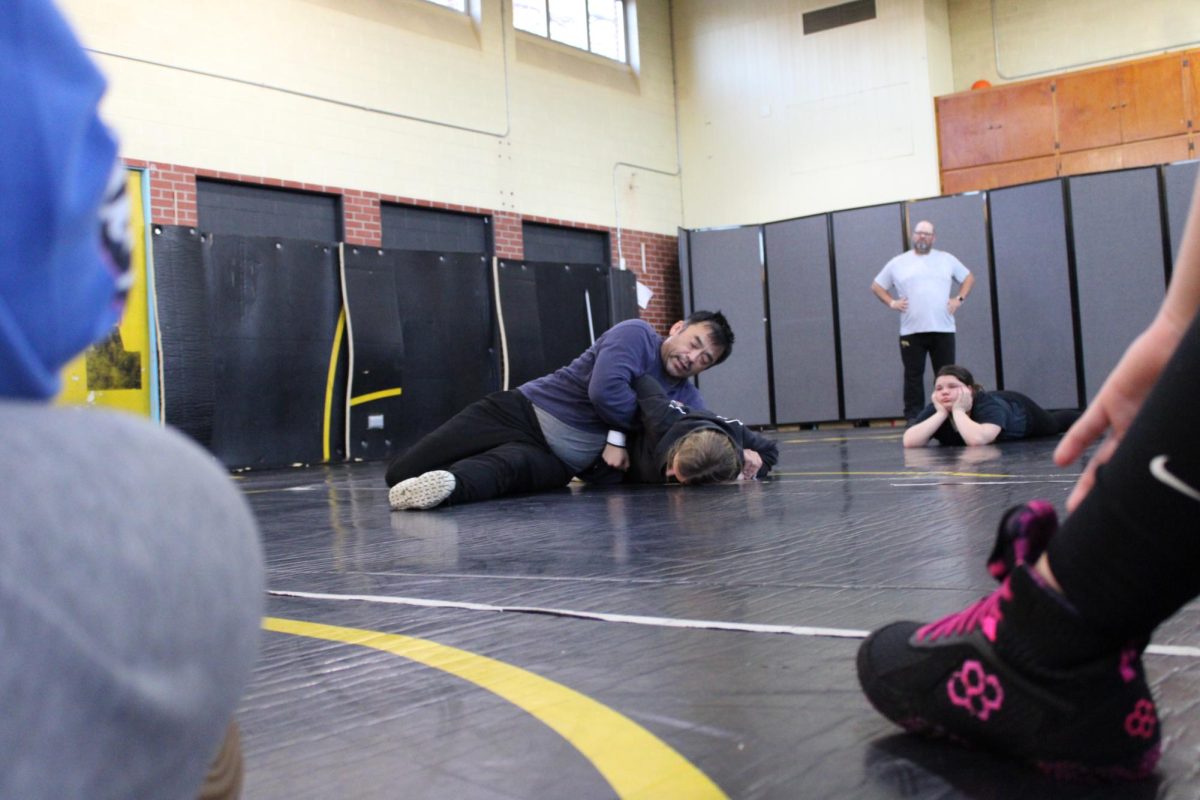 Junior Cadence Kinzie and Coach Grieving were demonstrating a move at wrestling practice while everyone else was watching. 